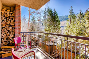Park Station 121s private balcony with two sitting chairs and trees and mountains beyond.