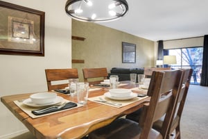 Park Station 122s dining room has a wood table, 6 chairs and place settings, and black circular chandelier.