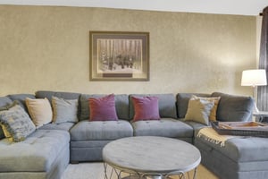 Park Station 122s living room has a grey upholstered sofa, throw pillows, modern round coffee table, and picture on the wall.