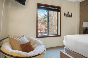 Park Station 122s main suite chair with throw pillows, TV, and large window.