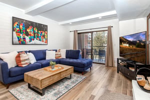 Park Station 133s living room has a blue sectional sofa, modern wood coffee table, and snowboard art on the wall.