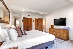 The main sutie has a kingsize bed, dresser, wall mounted flatscreen TV and two closets with wood doors.