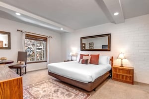 The main suite has a king size bed, area rug, and a large window overlooking town.