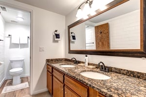 The main suite has an en suite bathroom with double sink vanity, large mirror, and granite counter tops.