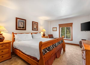 Park Station 134s main suite with a king size bed, white linens and pillows, and a window with trees outside.