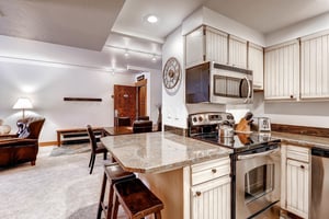 Park Station 134s kitchen with breakfast bar with seating for two, granite counters, and stainless steel microwave and oven.