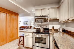 Park Station 134s kitchen with breakfast bar with seating for two, granite counters, and stainless steel microwave and oven.34Kitchen