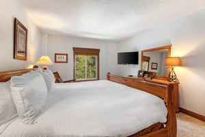 Park Station 134s main bedroom with king size bed, white linens and pillows, wooden bedframe, and wooden dresser.