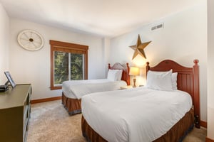 Park Station 134s second bedroom with two twin beds, white linens, wood bedframes, and large star in between the beds.