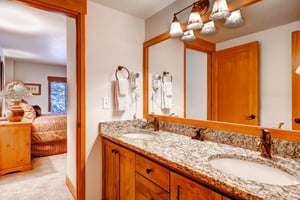 Park Station 134s shared bathroom with two sink wood vanity with large mirror and light above.