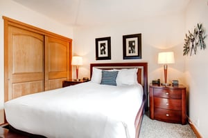The second bedroom has a queen size bed and wooden furniture.