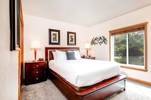 The second bedroom has a queen size bed and wooden furniture.