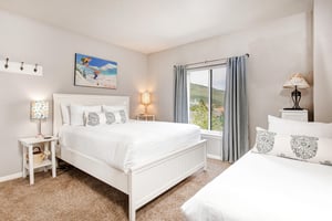 The second bedroom has a queen bed and white furnishings.