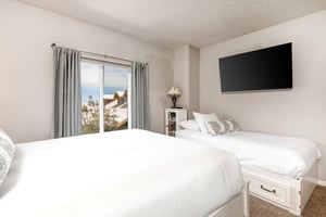 The second bedroom has a queen bed, twin bed, and white furniture.