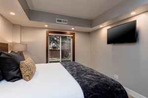 Comfortable king bed in the main bedroom with large picture window and wall mounted flat screen TV