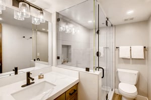 Beautifully updated bathroom with glass paneled shower, bullicante  glass vanity lighting