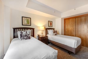 The second bedroom has two twin beds with white linens, wood bedframes, and fun animal print pillows to match.
