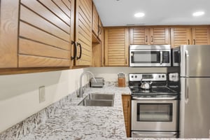 Park Station 214s kitchen offers stainless steel appliances, wood cabinets, and grey and white counter tops.