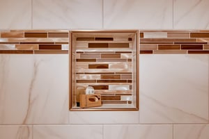 The shared bathroom has gorgeous white tile, with gold and brown decorative tile lining a shelf in the bathtub surround.