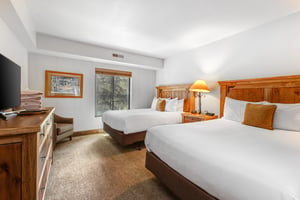 The main suite has two queen size beds and wood furnishings.