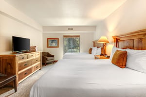 The main suite has two queen size beds and wood furnishings.