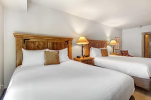 The main suite has two queen size beds and wood furnishings.