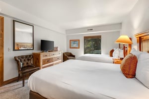 The main suite has two queen size beds and wood furnishings.