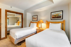 The second bedroom has two twin beds and wooden furniture.