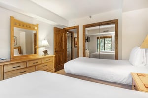 The second bedroom has two twin beds and wooden furniture.