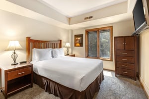 One of the bedrooms offers a queensize bed and wood furniture.