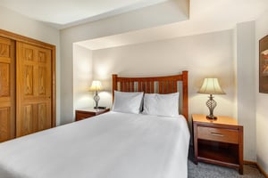One of the bedrooms offers a queensize bed and wood furniture.