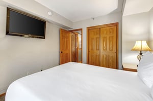 One of the bedrooms offers a queensize bed and wood furniture.