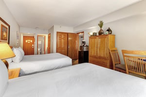 One of the bedrooms offer two queen beds with wooden furniture.