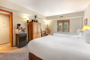 One of the bedrooms offer two queen beds with wooden furniture.