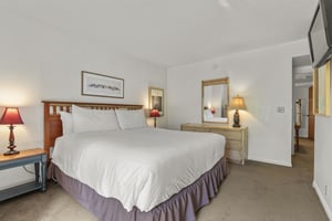 The main suite has a king size bed and wooden furniture.