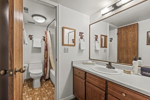 The en suite bathroom has a single sink vanity a separate water closet.