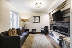 Building 1 lobby entrance lounge area, large area rug, dark gray sofa and black leather accent chair