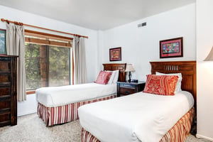 The second bedroom offer two twin beds with wooden furniture.