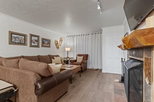 The living room has a large sectional sofa and curtains that cover the sliding glass door.