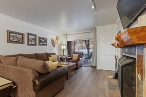 The living room has a large sectional sofa and sliding glass doors leading to a private patio.