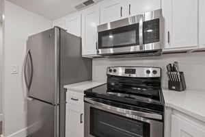 The kitchen has stainless steel appliances and white cabinets.