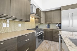 Open concept kitchen with waterfall island and stainless steel appliances.