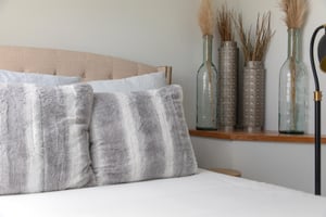 The queen size bed with stylish decor and throw pillows.