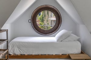 The twin bed with twin trundle and a round window overlooking town.