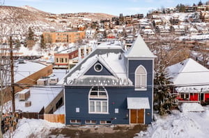Blue Church Lodge exterior with the snowy Historic Main Street in Park City and Park City Mountain behind.