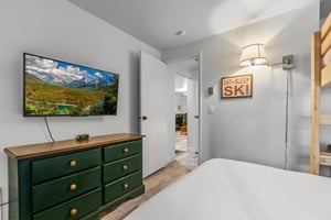 The second bedroom offers a green dresser and flat screen TV.
