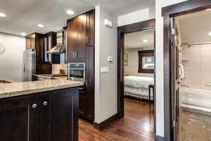 The wellequipped kitchen has dark wood cabinets, stainless steel appliances and bedroom off the kitchen.