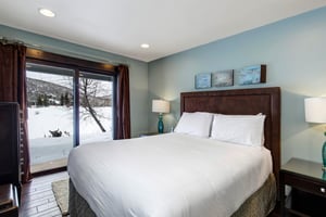 Another bedroom with a queen size bed and sliding glass doors with mountain and lake views.