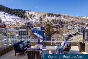 Rio Grande rooftop sitting area with fire table overlooking snow covered mountains.