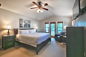 Main bedroom suite, glass patio door to private deck, vaulted ceiling and wooden blade ceiling fan, white duvet and king bed